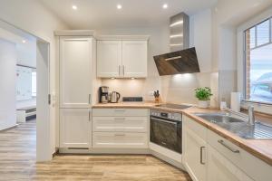 a kitchen with white cabinets and a sink at Kanalkajüte Theodor in Hanerau-Hademarschen