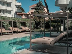 a pool with chairs and an umbrella next to a building at Prinsotel La Pineda in Cala Ratjada