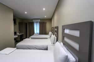une chambre d'hôtel avec deux lits et une salle de bain dans l'établissement PLM Palace Lodge, à Durban