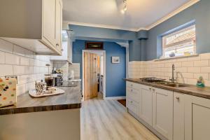 a kitchen with white cabinets and a blue wall at Bond Cottage in Overstrand