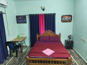 a bedroom with a bed with red sheets and a table at sarangvilla homestay varkala,edava in Kappil