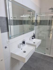 a white bathroom with two sinks and a shower at L8 Street - Mönsheim in Mönsheim
