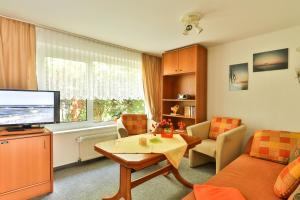 Una sala de estar con un sofá y un televisor. en Bungalow Bernstein, en Ostseebad Nienhagen