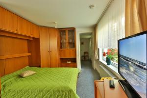 1 dormitorio con 1 cama verde y TV de pantalla plana en Bungalow Bernstein, en Ostseebad Nienhagen 10 fotos más