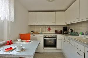 Una cocina con gabinetes blancos y una mesa con platos encima. en Bungalow Bernstein, en Ostseebad Nienhagen