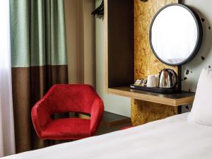 a bedroom with a red chair and a mirror at ibis Styles Bournemouth in Bournemouth +64 photos