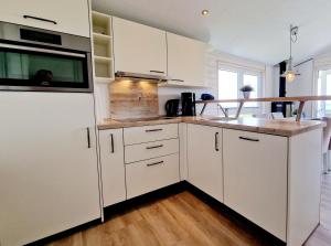 Una cocina con gabinetes blancos y un refrigerador blanco. en Ostseeferienpark Walkyrien - Kapitän 20, en Kagelbusch