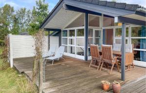 a house with a wooden deck with a table and chairs at 3 Bedroom Stunning Home In Rødby in Bjergemark +10 photos