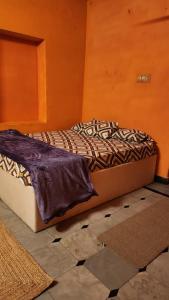 Cama en habitación con pared de color naranja en Tom's place hampi, en Hampi