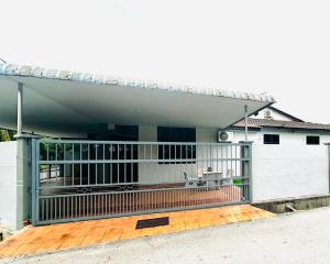 a white building with a gate and a wooden deck at Effa Homestay in Sungai Petani