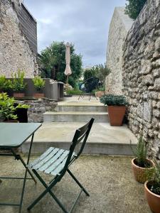 eine Terrasse mit einem Tisch, einem Stuhl und einem Sonnenschirm in der Unterkunft Maison cosy pour 2 à Crépy, véranda et jardin in Crépy-en-Valois