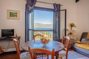 Un comedor con una mesa y un gran ventanal. en Casa Olivia, en Saint-Florent