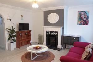 a living room with a purple couch and a fireplace at House - Sleeps 8 - Garden - Parking in Romford