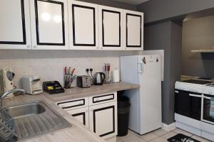 a kitchen with white cabinets and a white refrigerator at House - Sleeps 8 - Garden - Parking in Romford