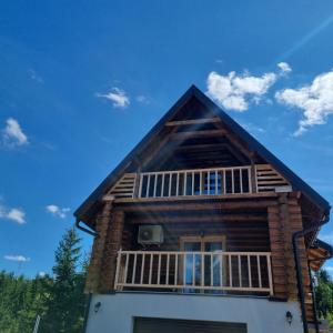 a log house with a balcony and a blue sky at Beloglavi sup in Nova Varoš