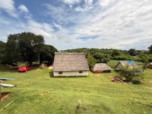 a house in a field with a red car in it at AVANI Stays in Yelagiri