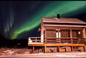 a cabin with the northern lights in the sky at Cabin with Sauna and Aurora Views in Karlsøy