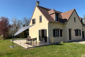 a house with a table and an umbrella in the yard at Maison de la Thillaye - Collection Idylliq in Saint-Étienne-la-Thillaye