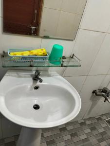 ein weißes Waschbecken in einem Badezimmer mit einem Spiegel in der Unterkunft Nhà Trọ Thuý Vy in Tri Tôn