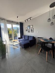 a living room with a blue couch and a table at Z Widokiem Apartamenty - apartamenty z widokiem na góry i zewnętrzną balią in Szklarska Poręba