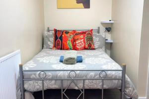a small bedroom with a bed with colorful pillows at House - Sleeps 10 - Garden - Parking in Romford
