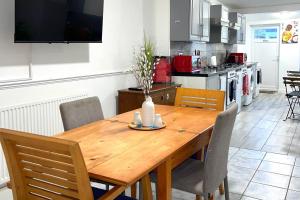 a kitchen with a wooden table with chairs and a kitchen with at House - Sleeps 10 - Garden - Parking in Romford +10 photos