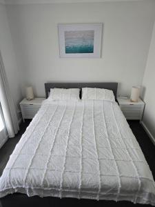 a bedroom with a large white bed with two night stands at Seas the Day in Lancelin