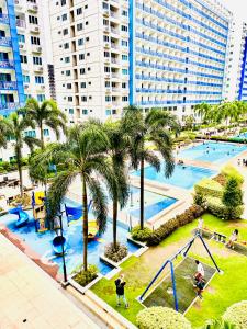 a playground with palm trees and people playing in it at Sea Residences MOA Manila by JO in Manila