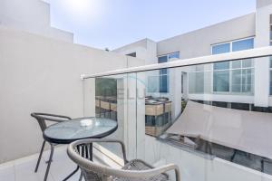 a balcony with a table and chairs on a building at Furnished 3-Bedroom Townhouse, Just Minutes Drive from Al Marmoom Heritage Village and Popular Dubai Attractions, Albizia, Damac Hills 2 by Deluxe Holiday Homes in Dubai