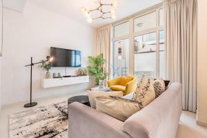 a living room with a couch and a tv at Furnished 3-Bedroom Townhouse, Just Minutes Drive from Al Marmoom Heritage Village and Popular Dubai Attractions, Albizia, Damac Hills 2 by Deluxe Holiday Homes in Dubai
