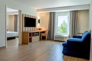 a hotel room with a blue couch and a television at Hampton Inn Torreon Airport-Galerias in Torreón