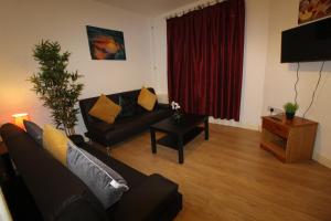 a living room with a black couch and a red curtain at Reeves House By Smart Corporate Stays in Derby