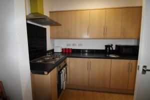a small kitchen with wooden cabinets and a stove at Reeves House By Smart Corporate Stays in Derby