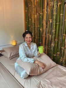 Una mujer sentada en una cama sosteniendo una taza verde. en Apartment El Nido, en El Nido