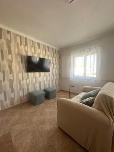 a living room with a couch and a television at Charm-In Apartments in Vila Nova de Milfontes