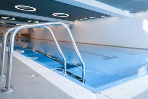 an indoor swimming pool with blue water and rails at SELF CHECK IN Arbed Living Apartments Arbedo Castione in Arbedo-Castione