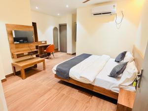 a bedroom with a bed and a desk and a television at Hotel City Inn 2min Walk To Gorakhnath Temple in Gorakhpur