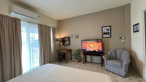 a bedroom with a bed and a tv and a chair at Ay’s House in Chiang Mai