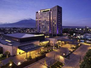 Un gran edificio con una montaña al fondo. en Grand Mercure Malang, en Malang