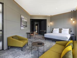 a hotel room with a bed and a couch at Pullman Tbilisi Axis Towers in Tbilisi City