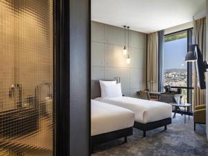 トビリシにあるPullman Tbilisi Axis Towersのベッドと机と窓のあるホテルの部屋 +130枚の写真