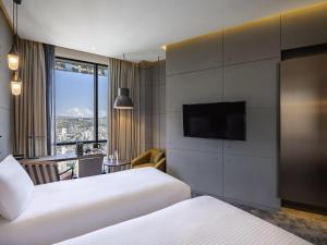 a hotel room with two beds and a flat screen tv at Pullman Tbilisi Axis Towers in Tbilisi City