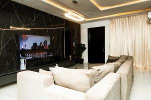 a living room with a white couch and a tv at Oasis Beautiful 2 Bedroom Shortlet Apartment in Lekki