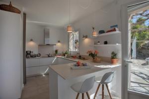 a kitchen with white cabinets and a island with stools at Casa Marinu Muntese in Erbalunga +22 photos