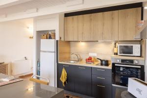 una cucina con armadi grigi e frigorifero bianco di Casa Sémaphore a LʼÎle-Rousse