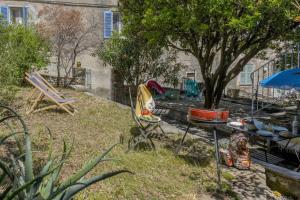 un patio trasero con sillas, una mesa y un árbol en La Bergerie, en Brando