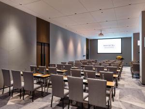 a conference room with tables and chairs and a projection screen at Novotel Dongguan Songshan in Dongguan