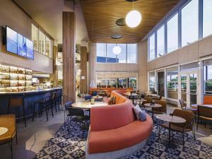 a restaurant with a couch and tables and chairs at Novotel Lencois Paulista in Lençóis Paulista