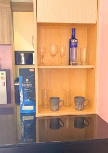 a shelf with cups and a bottle of wine at Chalong pool villa in Ban Na Bon