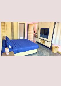 a bedroom with a blue bed and a flat screen tv at Chalong pool villa in Ban Na Bon
